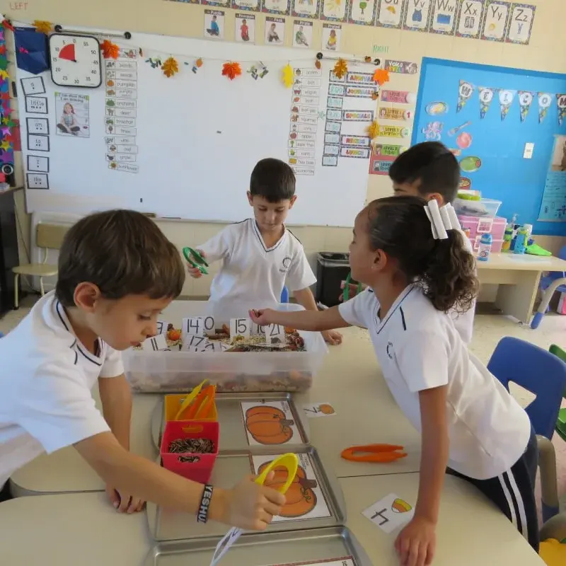 Estudiantes realizan actividad práctica con números y materiales educativos en el aula de primaria